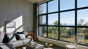 Ein modernes Wohnzimmer mit großem Fenster, einer Couch, einem Couchtisch und einem Sessel.
