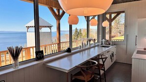 Una cocina con un ventanal grande con vistas al agua, una terraza de madera y un mirador.
