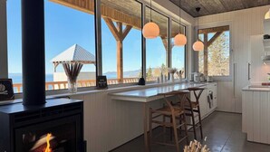 Una cocina moderna con una isla grande, vigas de madera en el techo y amplias ventanas con vistas panorámicas.