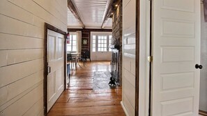 A hallway with wooden floors, white walls, and a white door on the right.