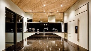 A modern kitchen with a granite countertop, stainless steel appliances, and a wooden ceiling. - Chalet Marée Basse | Charlevoix (La Malbaie)