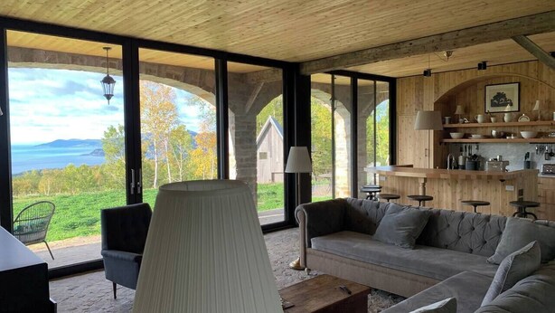 Una sala de estar moderna con un ventanal grande, un sofá, una lámpara y vistas al exterior.