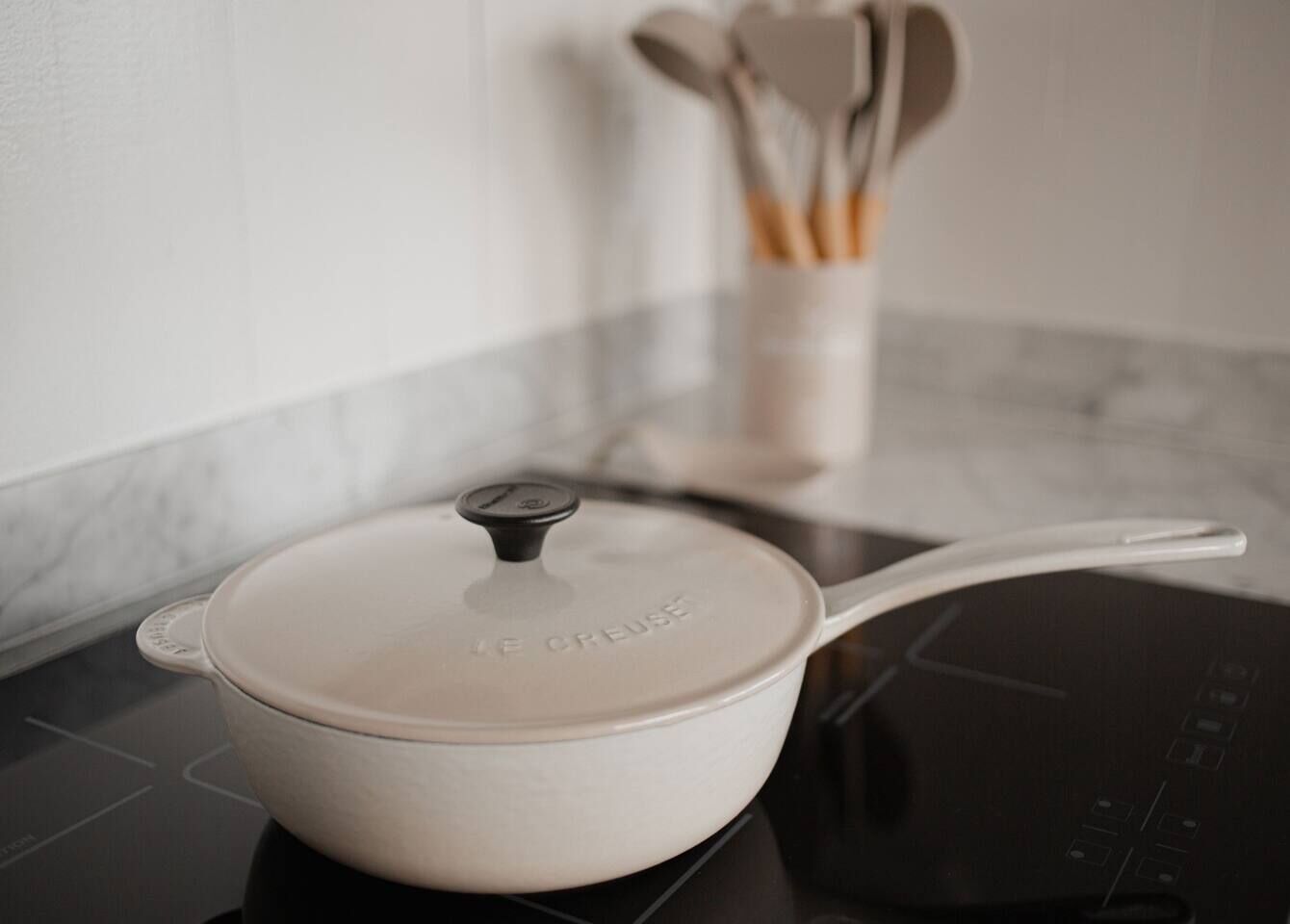 Una olla blanca de Le Creuseu sobre una cocina de inducción.