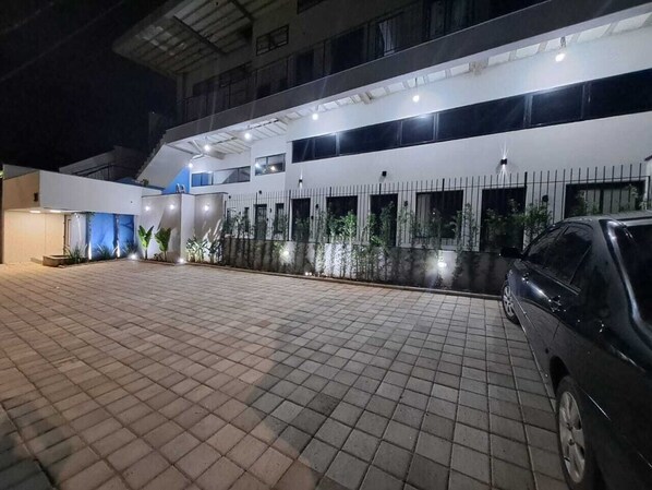 A modern building with a tiled driveway and a parked car.