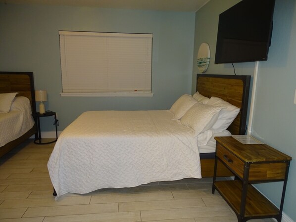 A bedroom with a bed, bedside table, lamp, and a mounted TV.