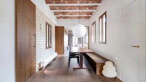 A modern interior with a long wooden bench, a white wall with a grid pattern, and a brick ceiling. - Barcelona Blissful Apartment Escape (Barcelona)