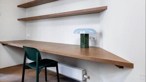 A workspace with a wooden desk, a green chair, and a wall-mounted lamp. - Barcelona Blissful Apartment Escape (Barcelona)