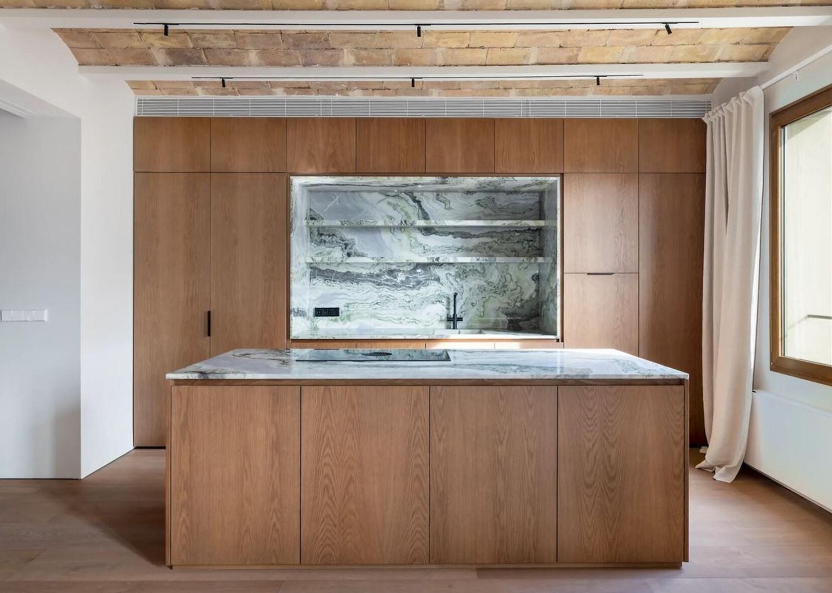 A modern kitchen with wooden cabinetry and a marble backsplash.