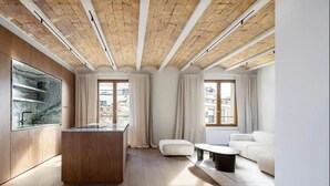 A modern living room with a wooden ceiling, a marble backsplash, and a white sofa. - Barcelona Blissful Apartment Escape (Barcelona)