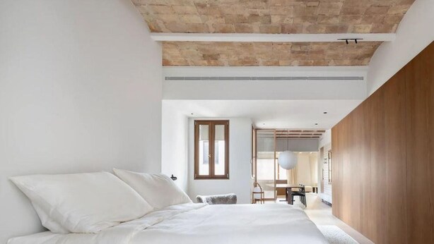 A modern bedroom with a wooden bed frame, a large window, and a view of a dining area. - Barcelona Blissful Apartment Escape (Barcelona)