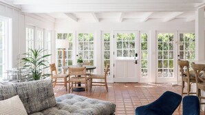 A bright, open-plan living area with a dining table, chairs, and a sofa. - Buttterfly Beach Dream Cottage (Montecito)