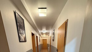 A hotel hallway with wooden flooring, doors on both sides, and framed pictures on the walls. - Eurocity Hotel (Bruchkoebel)
