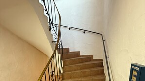 A staircase with a metal railing, beige steps, and a wall-mounted light switch. - Eurocity Hotel (Bruchkoebel)