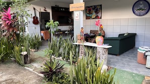 Un espace d’accueil avec un canapé vert, une petite table sur laquelle est posé un vase, et diverses plantes.
