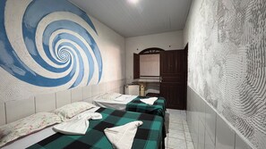 A room with two beds, a large blue and white spiral artwork on the wall, a wooden cabinet, and a patterned wall.