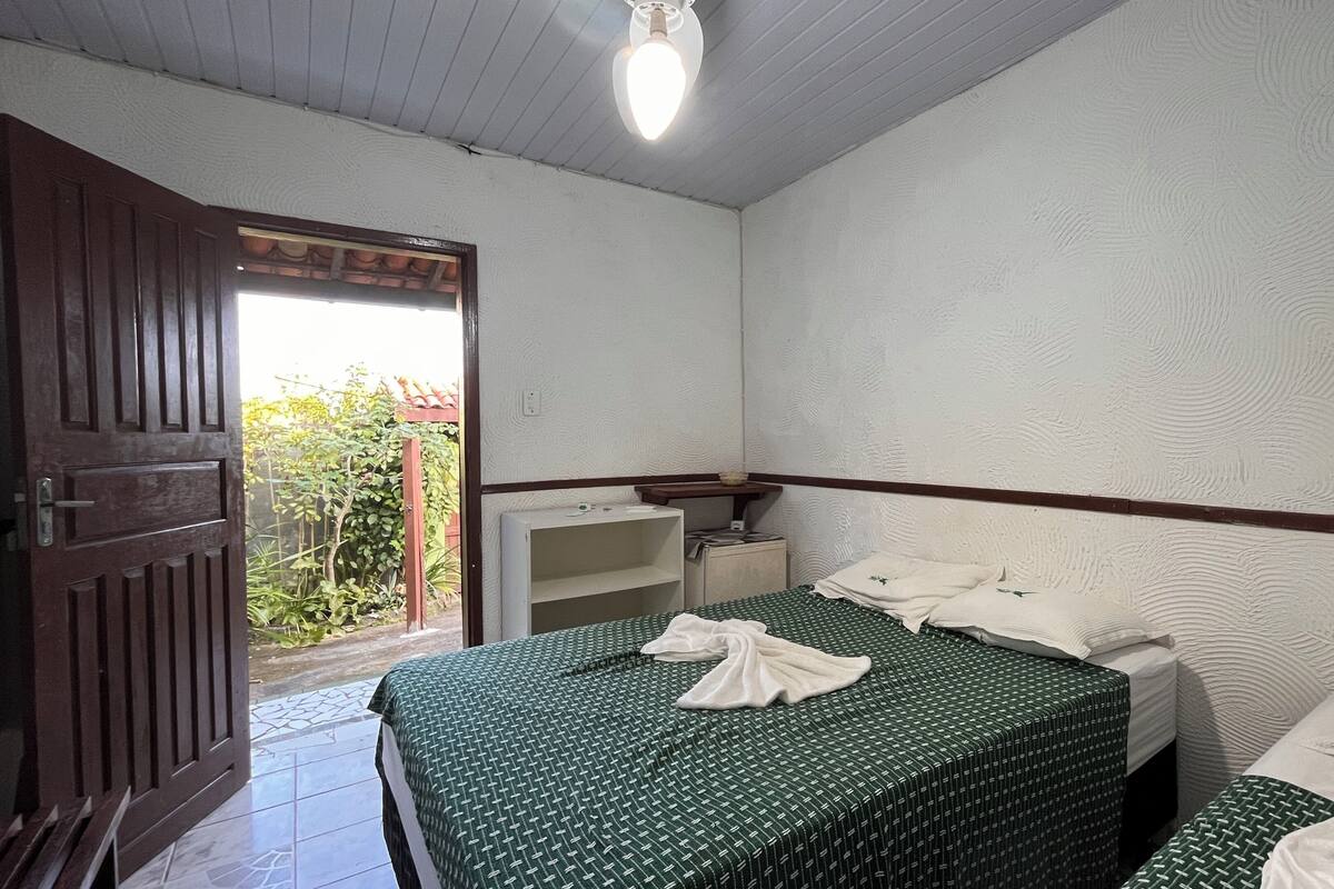 Una habitación pequeña y limpia con una cama, una mesita de noche y una ventana.