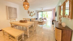 A spacious living area with a dining table, chairs, a bench, a wooden cabinet, and a large chandelier. - 2BR 6 Guest Balcony in Portillo Close to Beach (Las Terrenas)