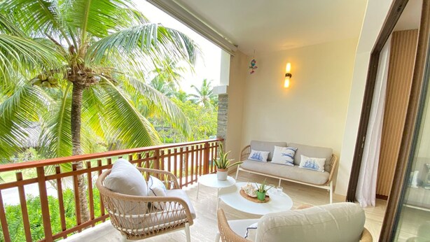 A balcony with wicker furniture, a sofa, and a small table. - 2BR 6 Guest Balcony in Portillo Close to Beach (Las Terrenas)