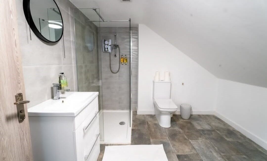 A modern bathroom with a shower, toilet, and sink.