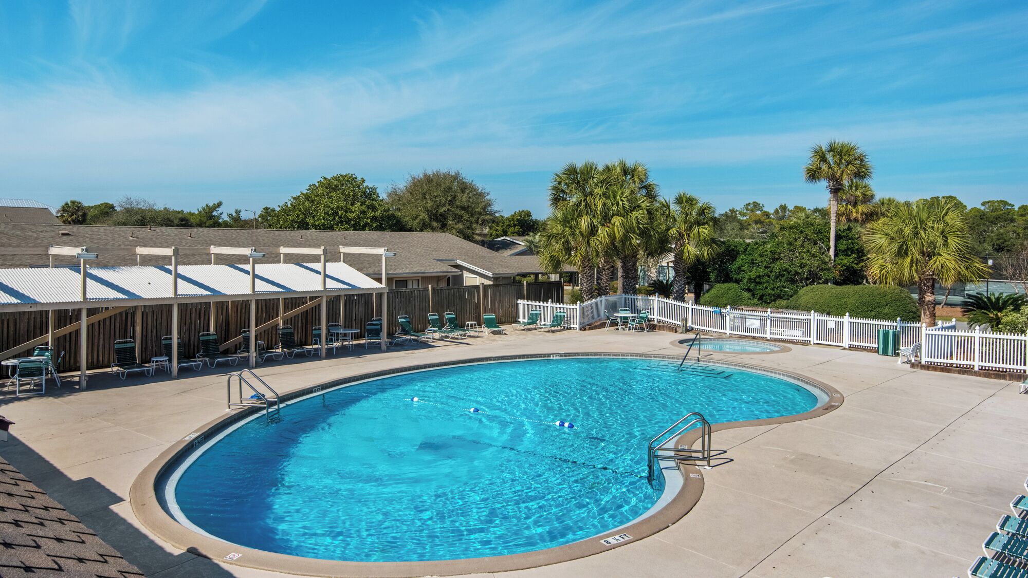 A swimming pool with a curved design, surrounded by lounge chairs and a covered seating area.