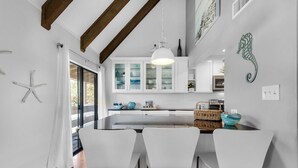 Una cocina moderna con armarios blancos, una isla central con taburetes de bar y una lámpara colgante.