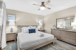 Cozy retreat with a large bed, nightstand, dresser, and ceiling fan.