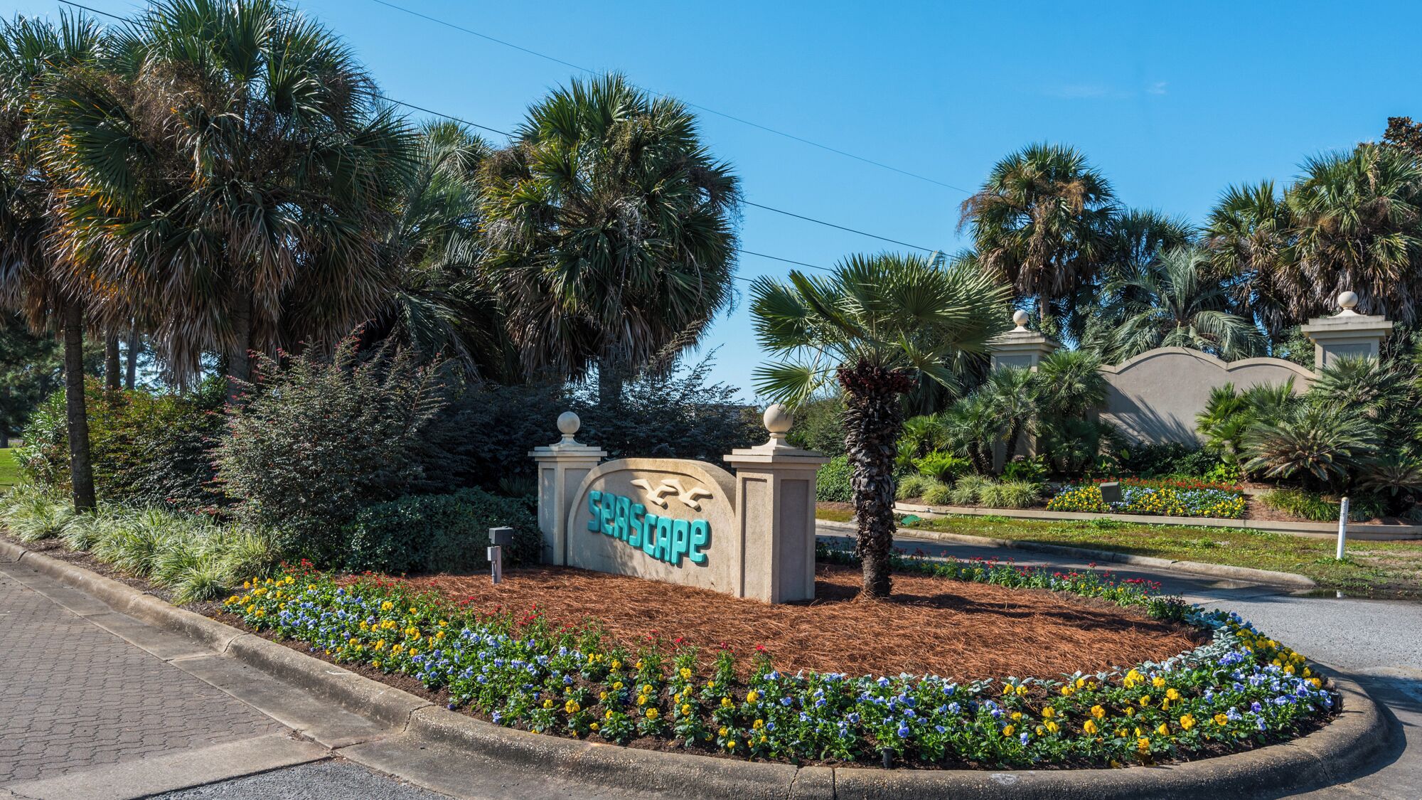 A landscaped entrance with a sign reading "Seascape" surrounded by a variety of plants and flowers.