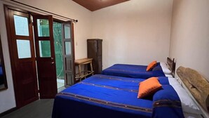 Un dormitorio con dos camas, un armario de madera y una mesita.