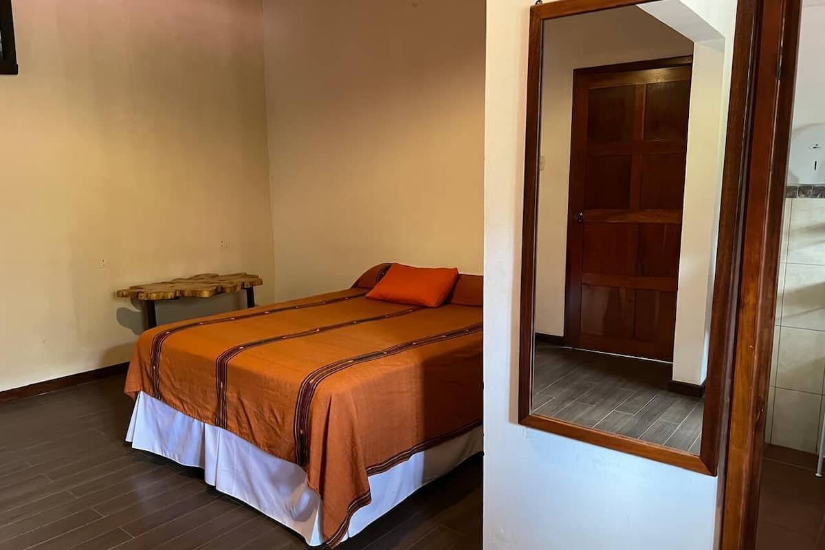 Un dormitorio con cama, un banco de madera y un espejo.