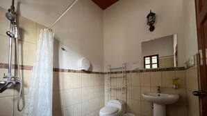 Baño con inodoro, lavabo, ducha y toallero.