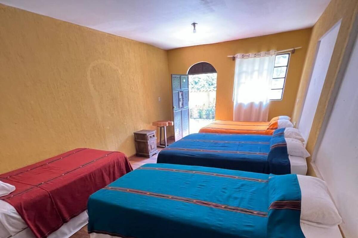Una habitación con dos camas, suelo de madera y una mesita.