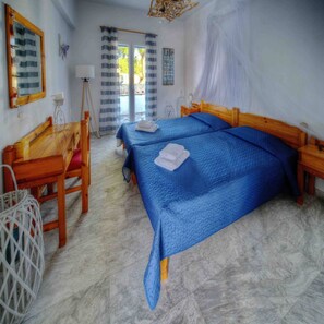 Una habitación con dos camas, un escritorio de madera, una silla, una lámpara y una ventana con cortinas.