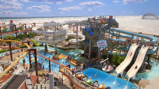 Un parco acquatico con diverse scivolate e piscine, circondato da una spiaggia sabbiosa.