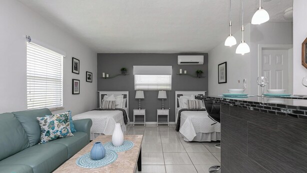 A modern, well-lit living room with a sofa, two beds, a kitchen area, and a dining table. - 1bd 1bth , PYT , Airport , MPT (Fort Lauderdale)