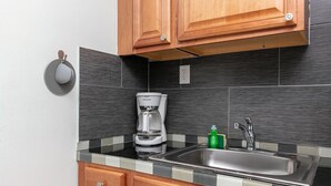 Eine Küche mit Kaffeemaschine, Spüle und Holzschränken.