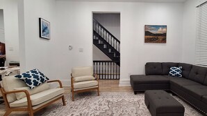 A living room with a sofa, armchair, and a patterned rug. - Diamond in the Burgh (Pittsburgh)