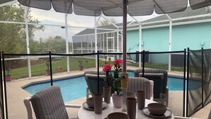 Ein überdachter Patio-Bereich mit Blick auf den Pool, Sitzmöglichkeiten im Freien und ein Tisch, gedeckt für das Essen.