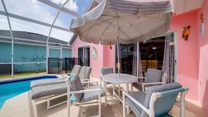 Ein überdachter Außenbereich mit Pool, Liegestühlen und einem Tisch.