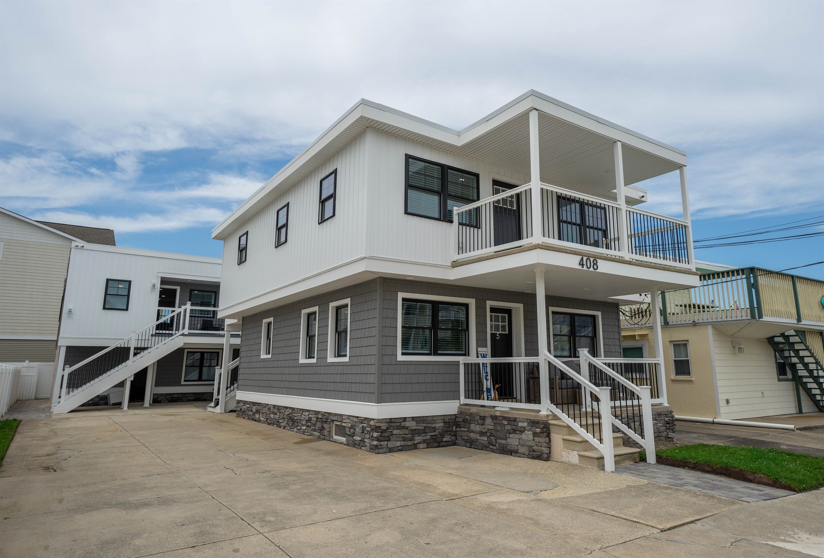 A two-story residential building with a balcony on the upper floor, a stone foundation, and a visible address number.