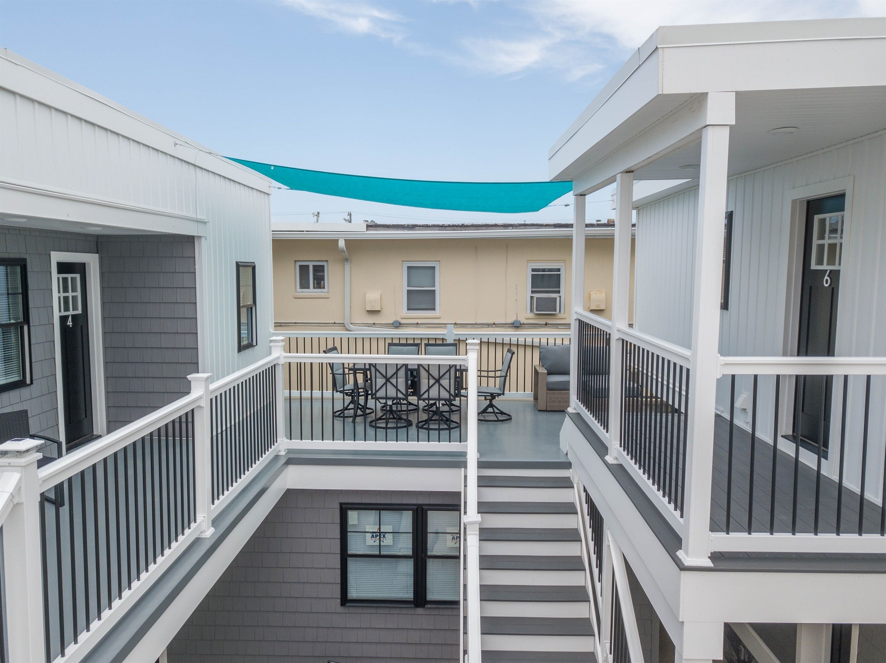 A multi-level residential building with a balcony, outdoor seating, and a staircase.