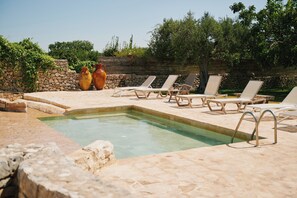 A pool area with lounge chairs and stone walls. - Masseria dei Preti (Conversano)