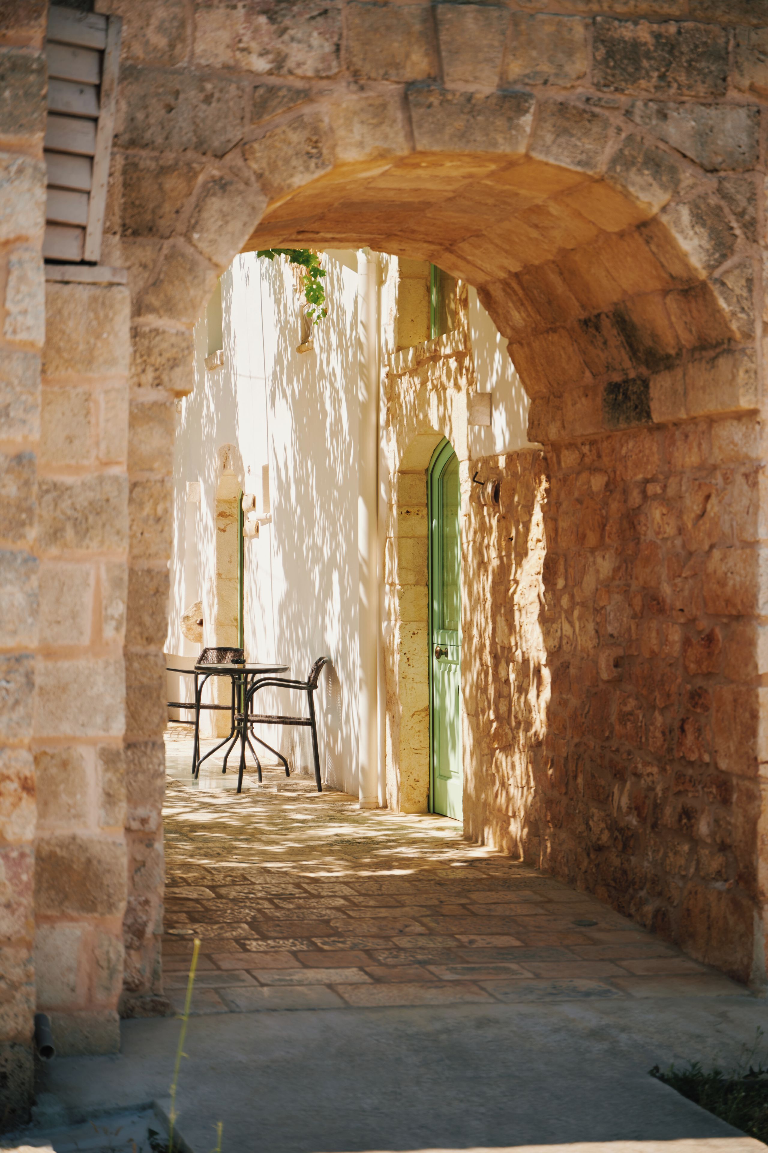 Un portale ad arco in pietra che dà su un cortile con tavolo e sedie.