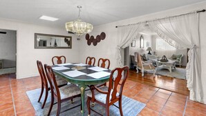 A dining area with a green table and wooden chairs, a chandelier, and a large mirror on the wall. - Central El Paso. 7 mins to Ft Bliss. (El Paso)