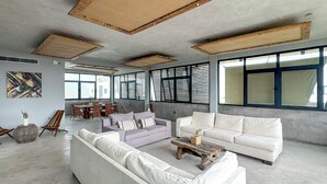 A spacious living area with a large sofa, a smaller sofa, and a coffee table. There is a dining table with chairs in the background. - Zel-va Tulum (Tulum)