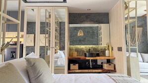 A modern bedroom with a large bed, a wooden wardrobe, a vanity with a mirror, and a hanging light fixture. - Zel-va Tulum (Tulum)
