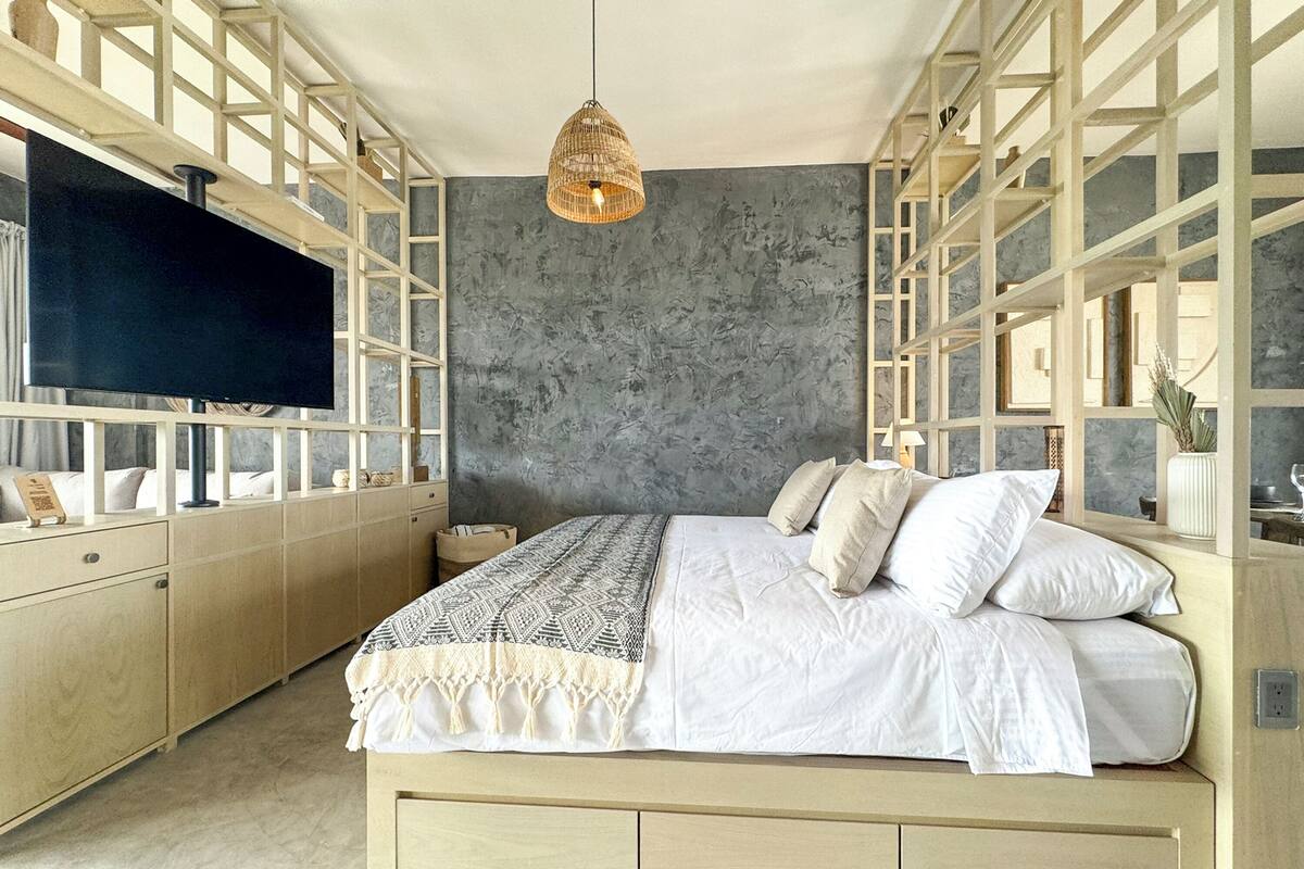 A bedroom with a bed, a TV, and a hanging light fixture.