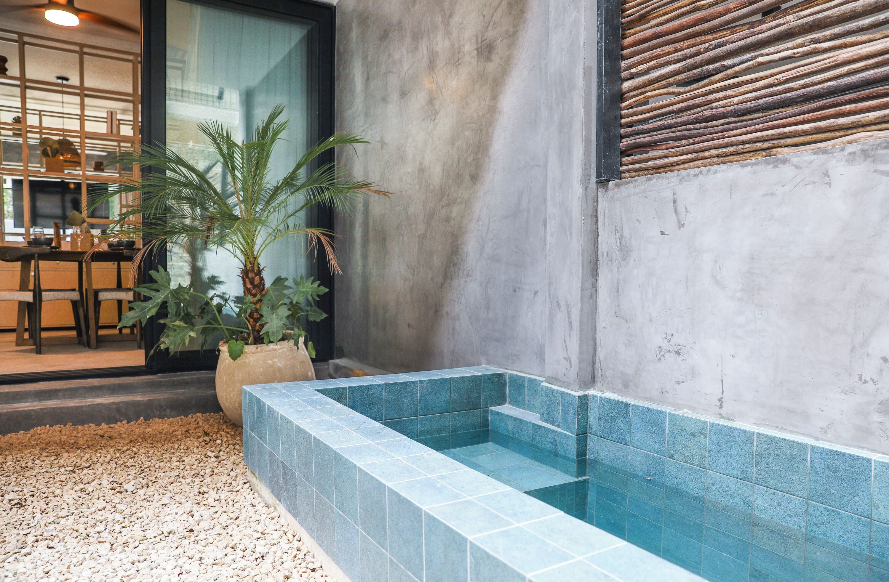 Un espace spa comprenant une petite piscine, un palmier et un coin salon avec une table et des chaises.