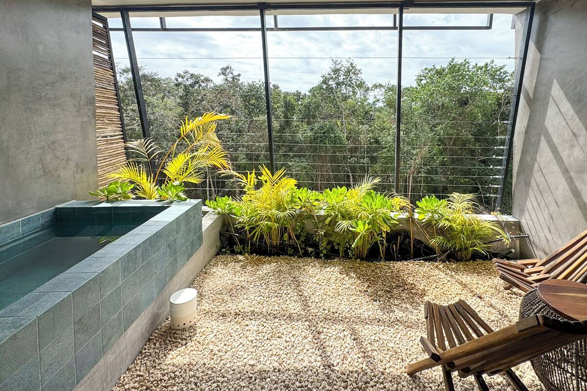 A modern balcony with a built-in planter, a seating area, and a view of the surrounding greenery.