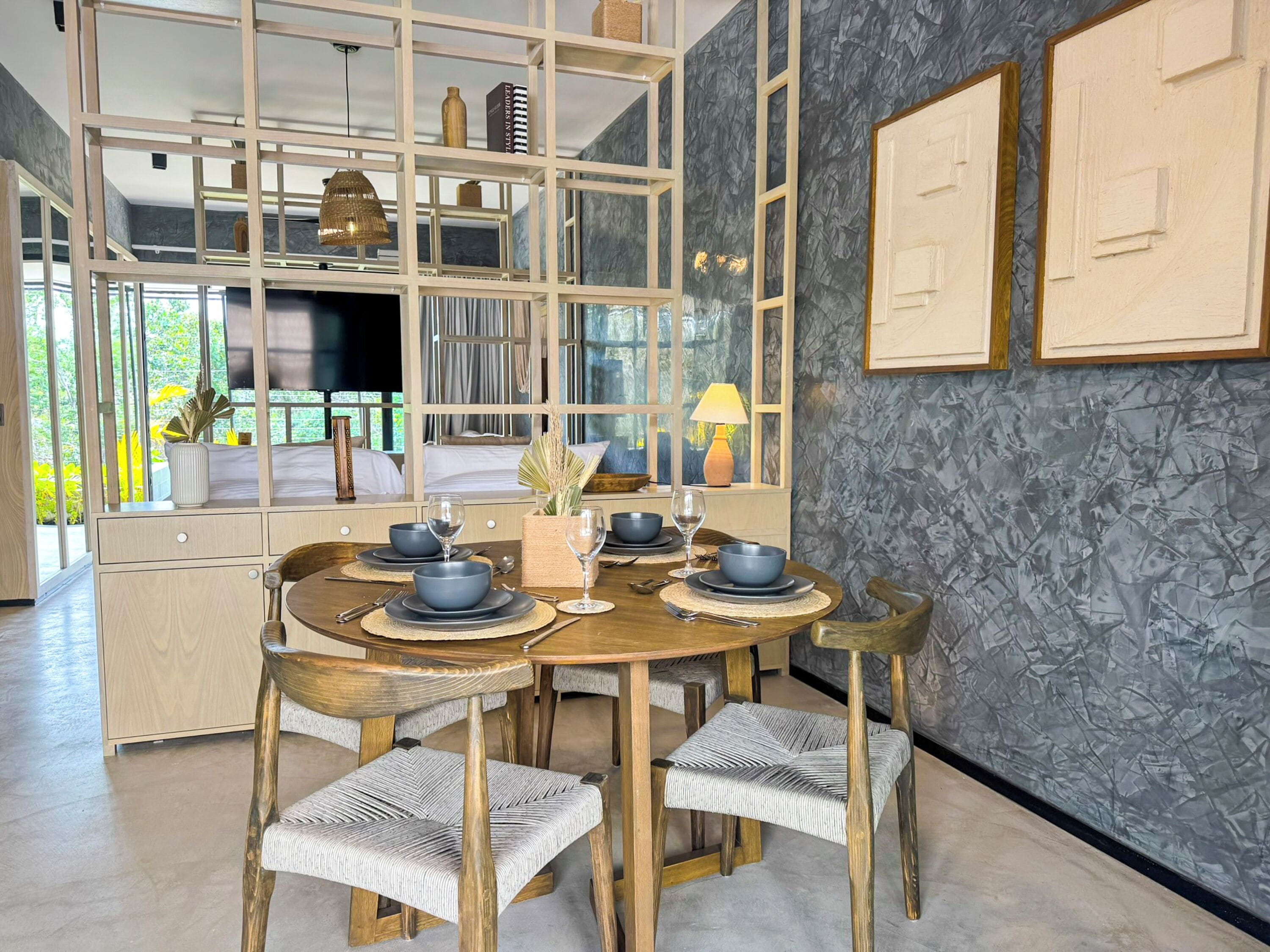 A dining area with a round wooden table, six chairs, and a central vase.