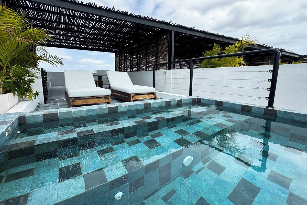A swimming pool with tiled steps and lounge chairs.